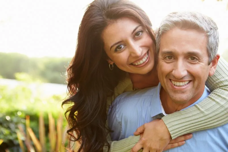 husband and wife embracing outside and smiling at the camera
